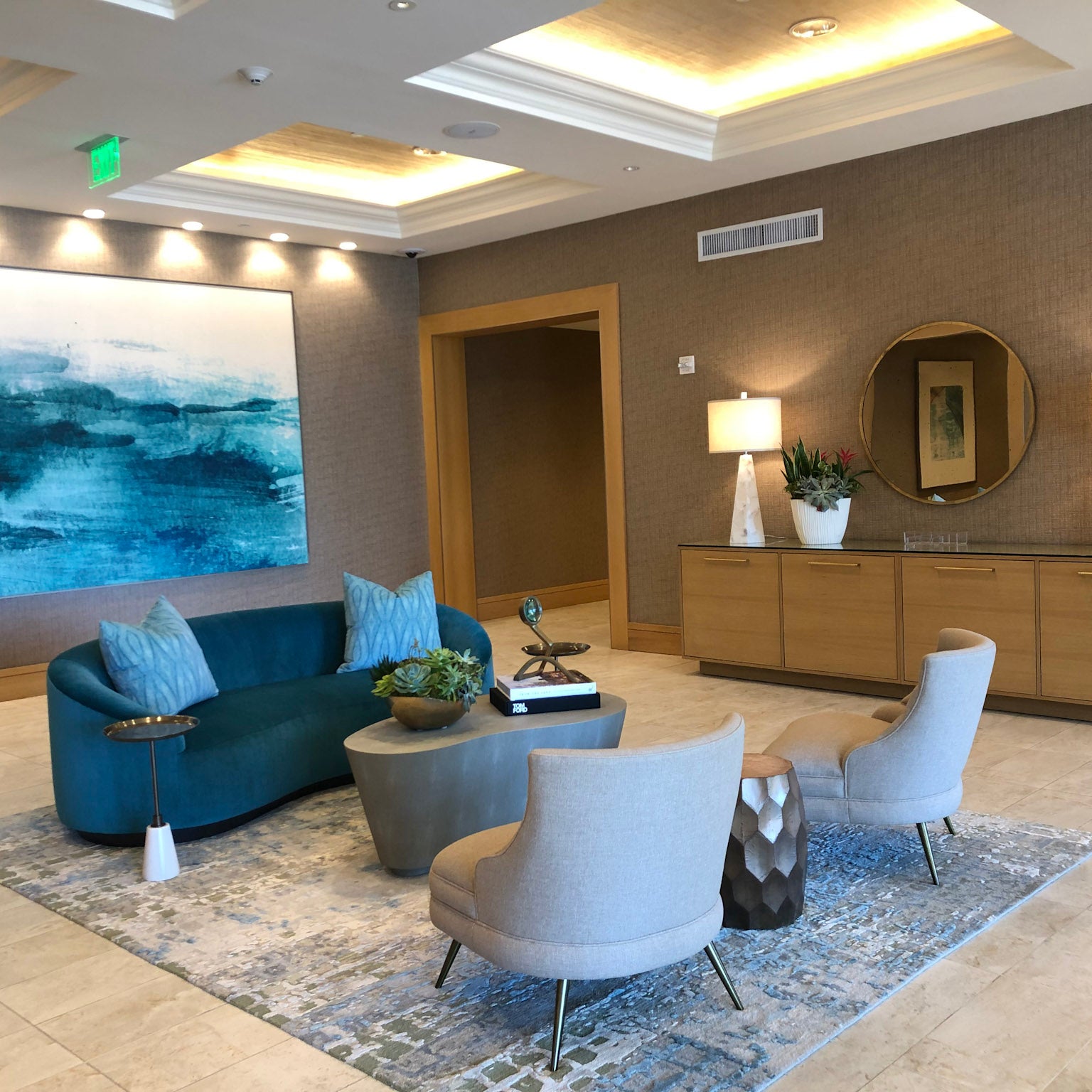 Chic reception area featuring a large, tranquil ocean-themed painting by WRAPPED Studio, complementing the upscale ambiance with its serene blue tones.