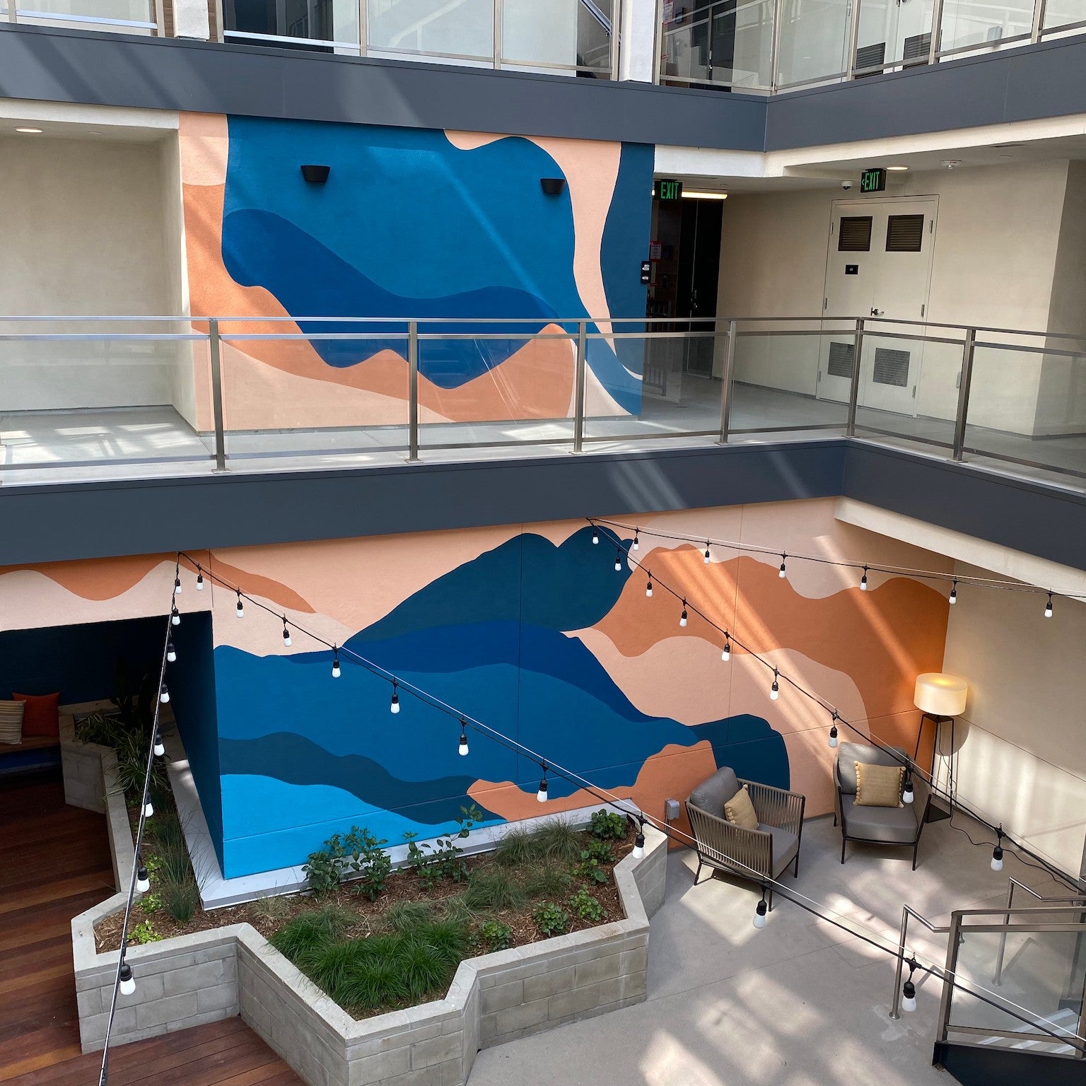 1641 Lincoln Apartments featuring an expansive, two-story hand-painted mural by WRAPPED Studio, with abstract oceanic shapes guiding tenants through the space.