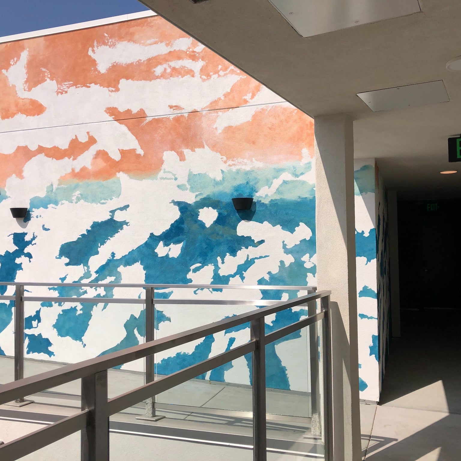 Balcony view at 1641 Lincoln with a hand-painted mural by WRAPPED Studio, showcasing a whimsical ocean watercolor effect that enhances the modern space.
