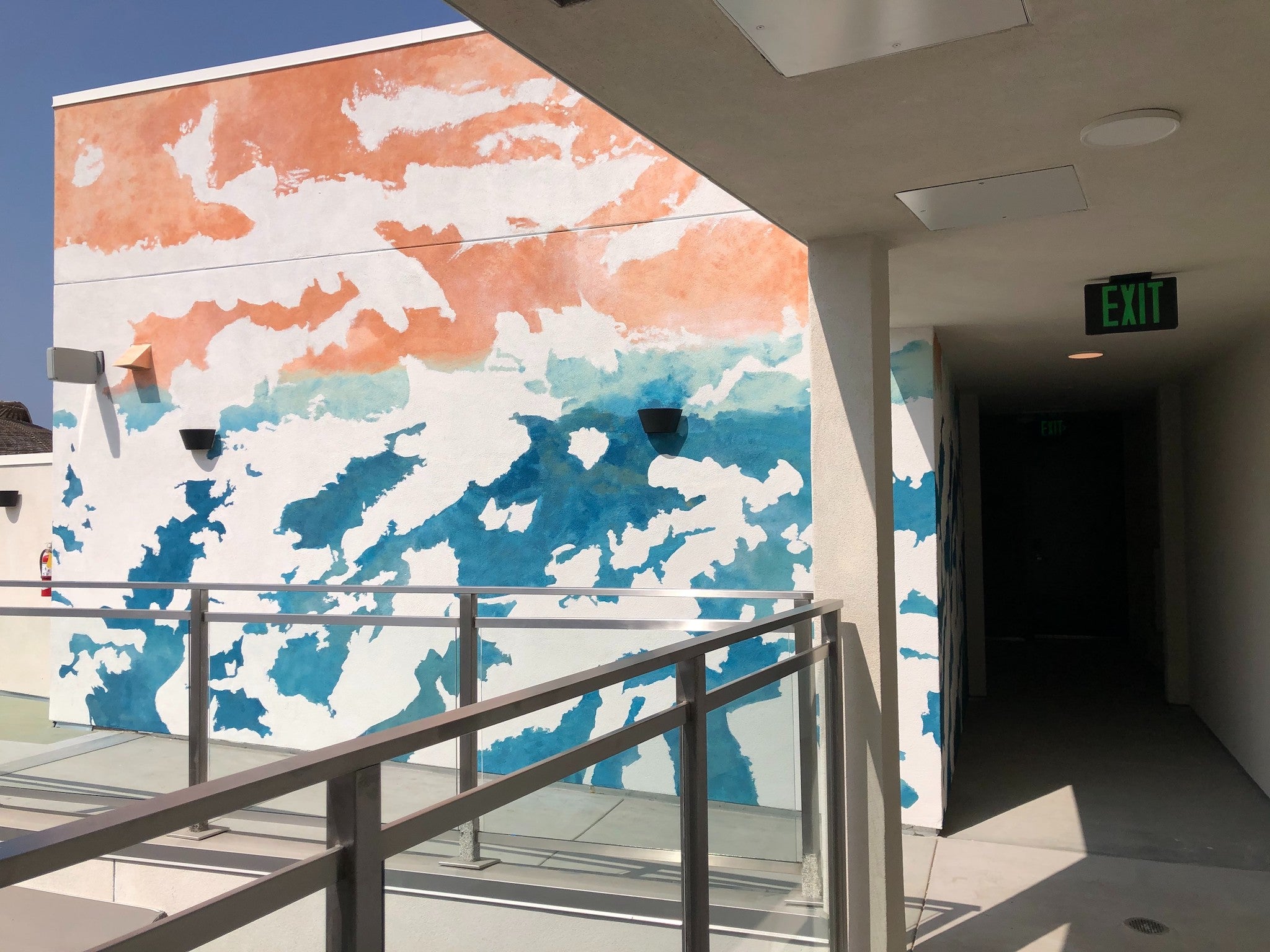 Balcony view at 1641 Lincoln with a hand-painted mural by WRAPPED Studio, showcasing a whimsical ocean watercolor effect that enhances the modern space.