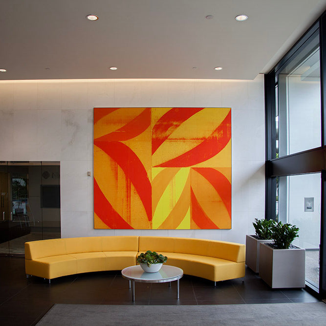 Bright and spacious lobby of 610 Newport Center Drive adorned with a vibrant orange and yellow abstract painting by WRAPPED Studio, reflecting Fashion Island's chic ambiance.