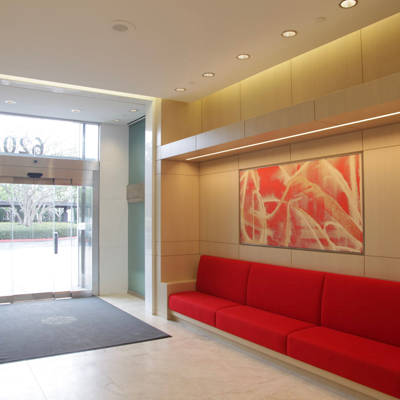 Modern lobby of 620 Newport Center with a striking red abstract painting by WRAPPED Studio, enhancing the welcoming ambiance with bold warmth.