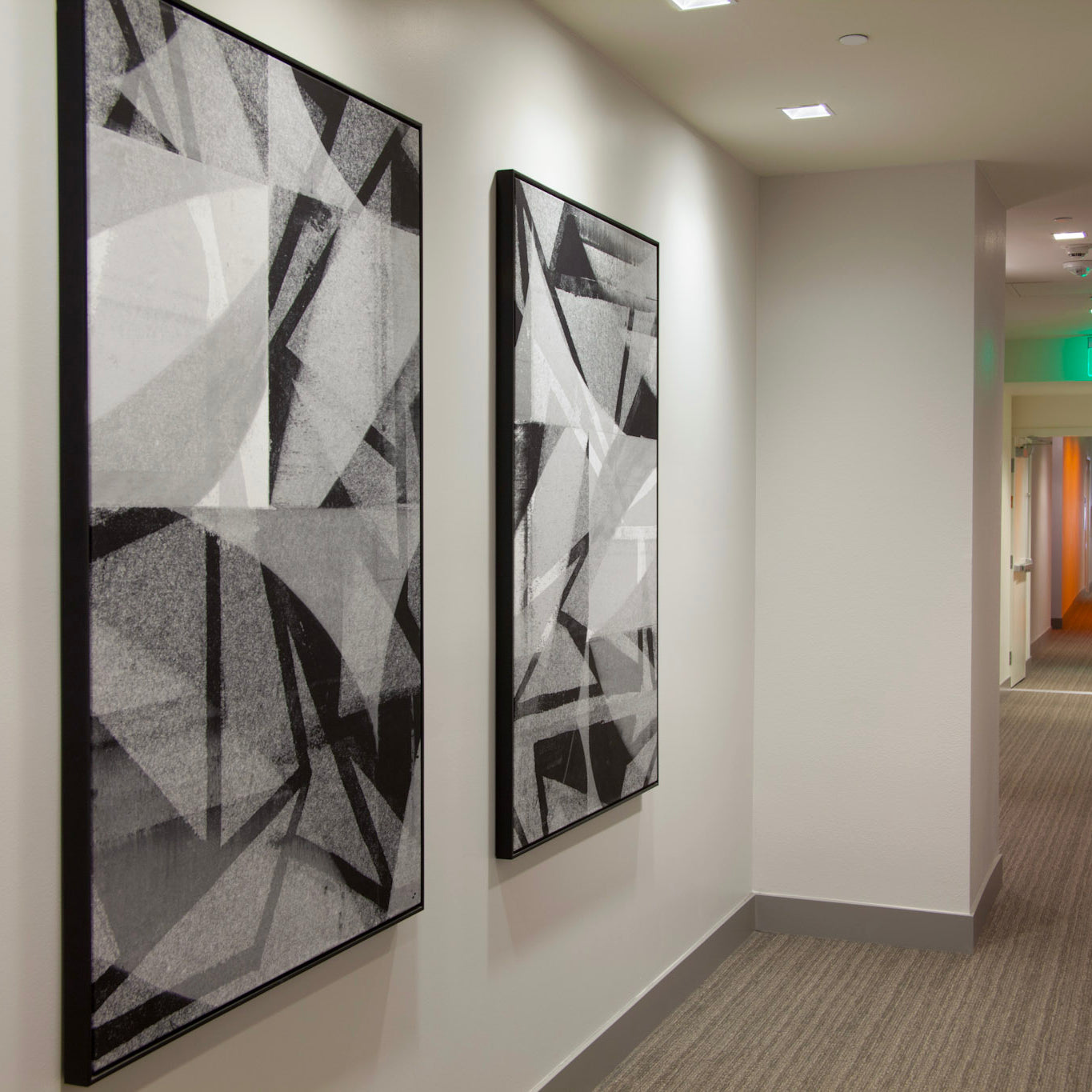 Hallway inside Alexan Aspect featuring bold geometric black and white canvases by WRAPPED Studios, complementing the upscale interior design.