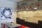 Multifamily residence dining area in Alexan Aspect with a striking black and white splash canvas by WRAPPED Studios, industrial chic wall decor and red accent lighting.
