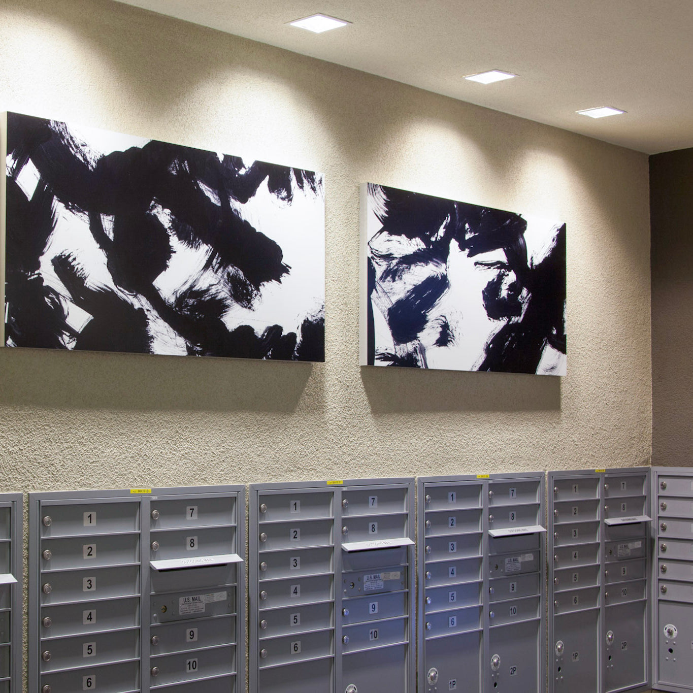Multifamily apartment mailroom at Alexan Aspect with black and white dynamic canvases above mailboxes, crafted by WRAPPED Studios.