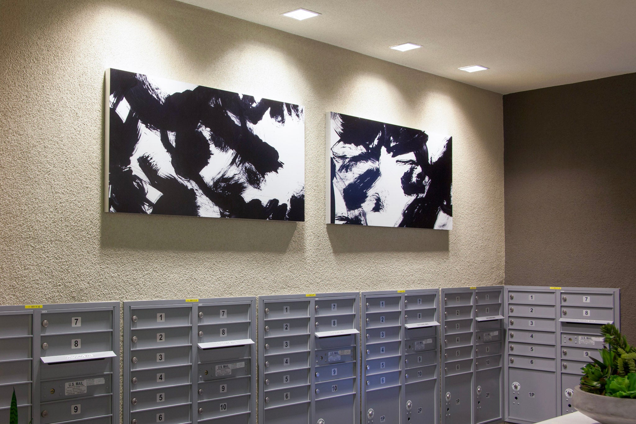 Multifamily apartment mailroom at Alexan Aspect with black and white dynamic canvases above mailboxes, crafted by WRAPPED Studios.