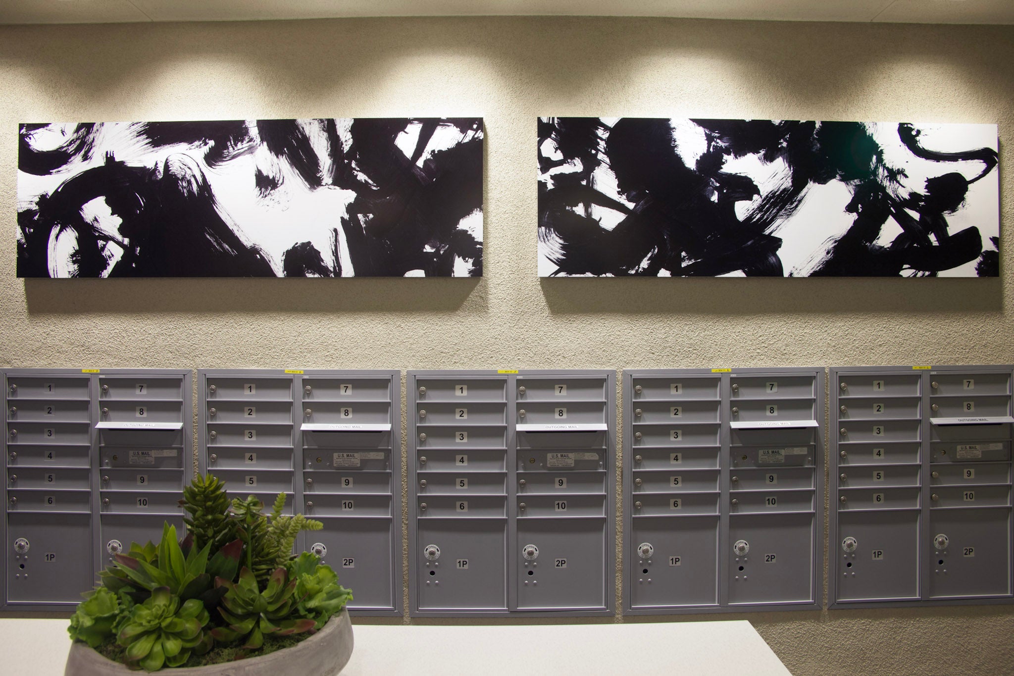 Mailroom at Alexan Aspect adorned with abstract black and green brushstroke art by WRAPPED Studios, injecting color into the sleek space.