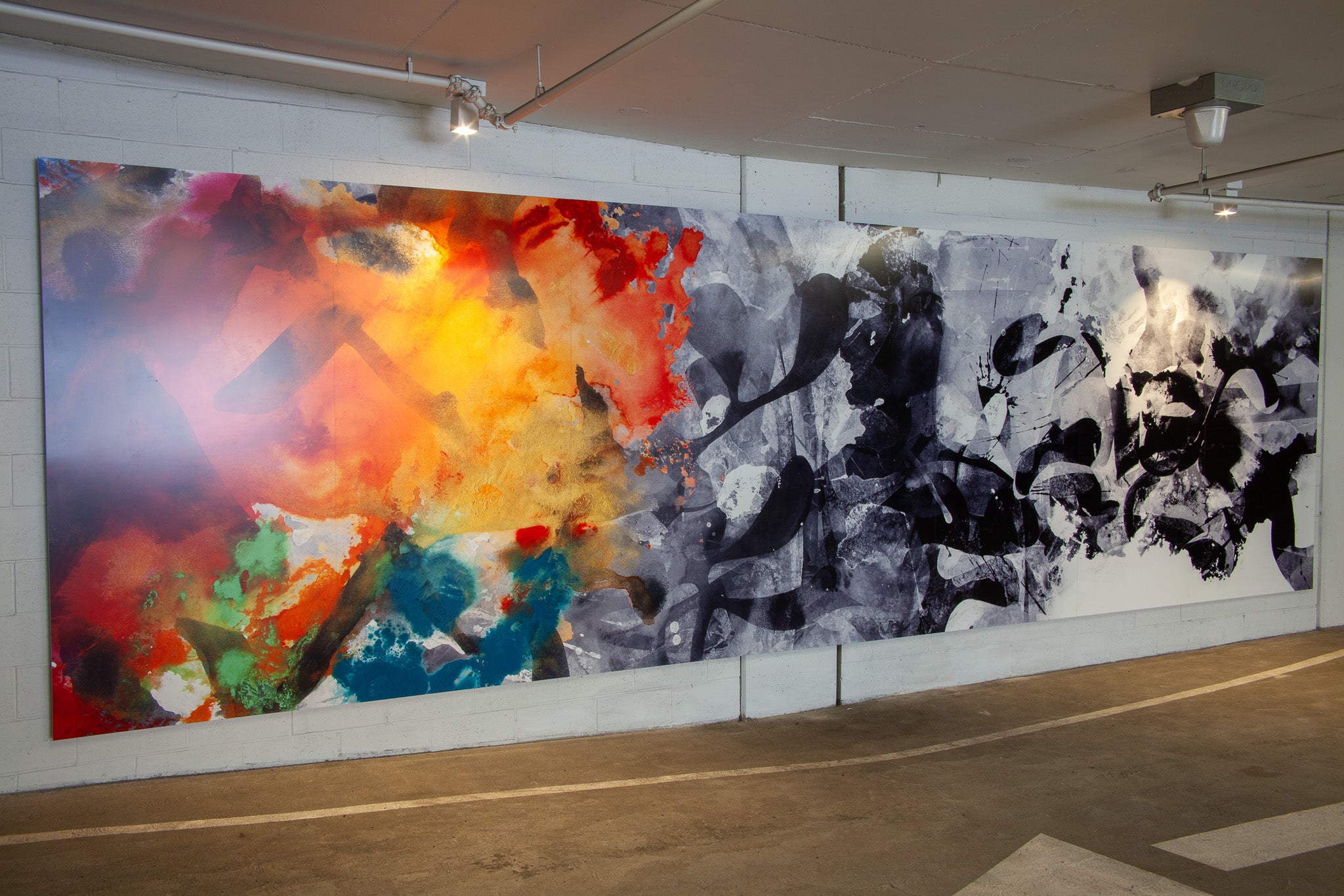 Large-scale diptych mural with vibrant color fields and black ink-like forms, designed by WRAPPED Studio for AMLI’s Uptown Orange garage wall.