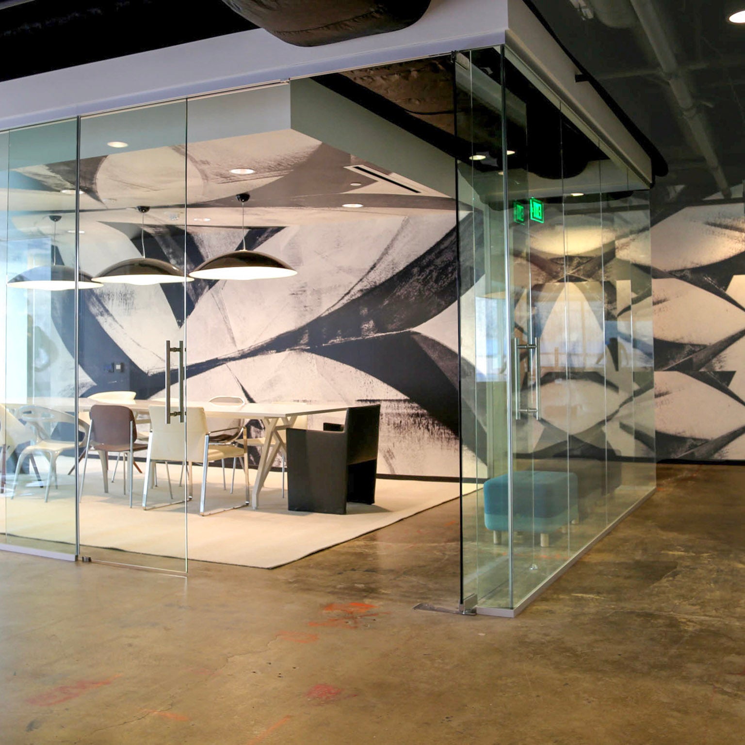 Chic conference room within Brookfield Design Hive with a custom black-and-white abstract wallcovering by WRAPPED Studio, inspired by Frank Stella's art, and modern lighting fixtures.
