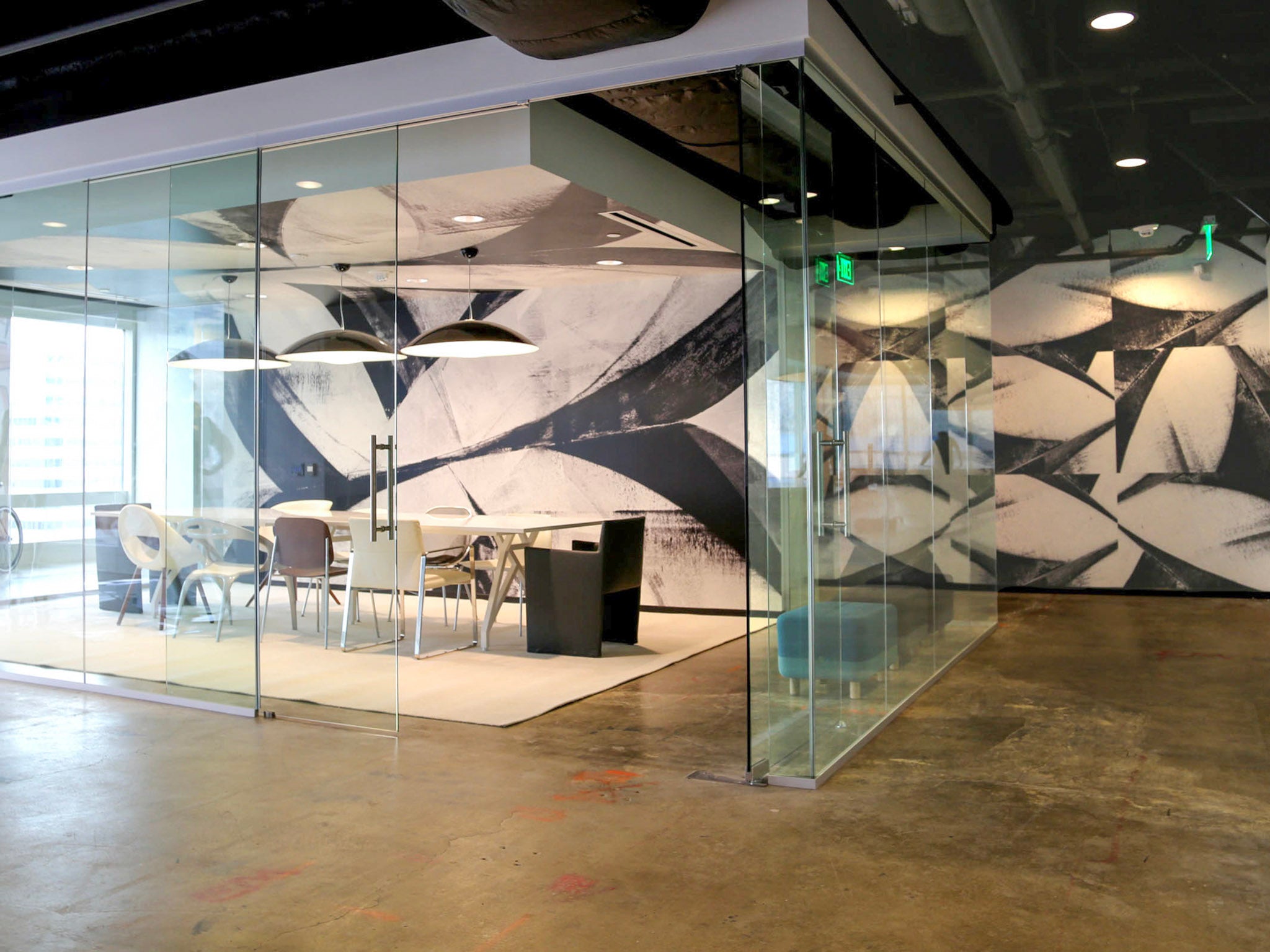 Chic conference room within Brookfield Design Hive with a custom black-and-white abstract wallcovering by WRAPPED Studio, inspired by Frank Stella's art, and modern lighting fixtures.