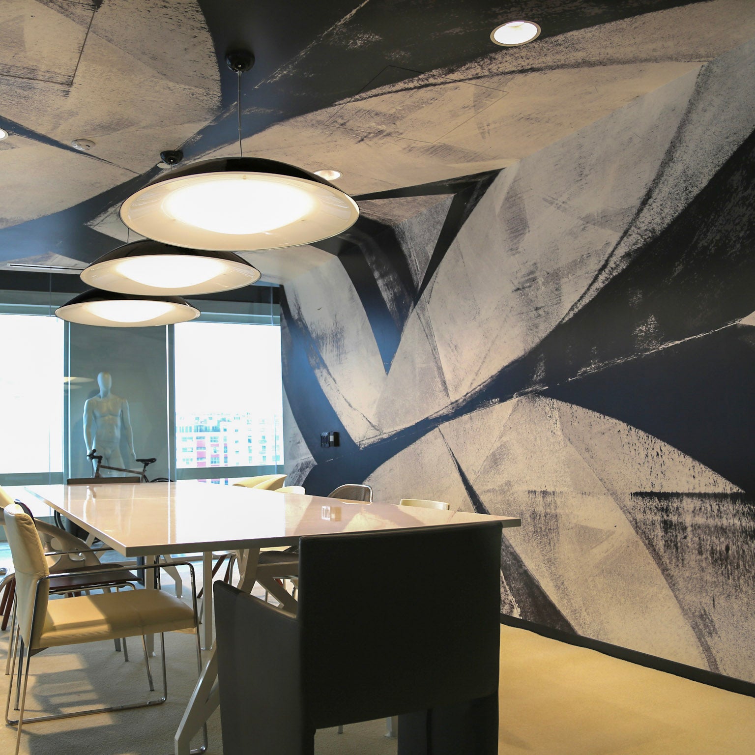 A modern meeting room at Brookfield Design Hive with floor-to-ceiling glass walls, featuring a dramatic black-and-white mural by WRAPPED Studio, fostering a creative workspace ambiance.