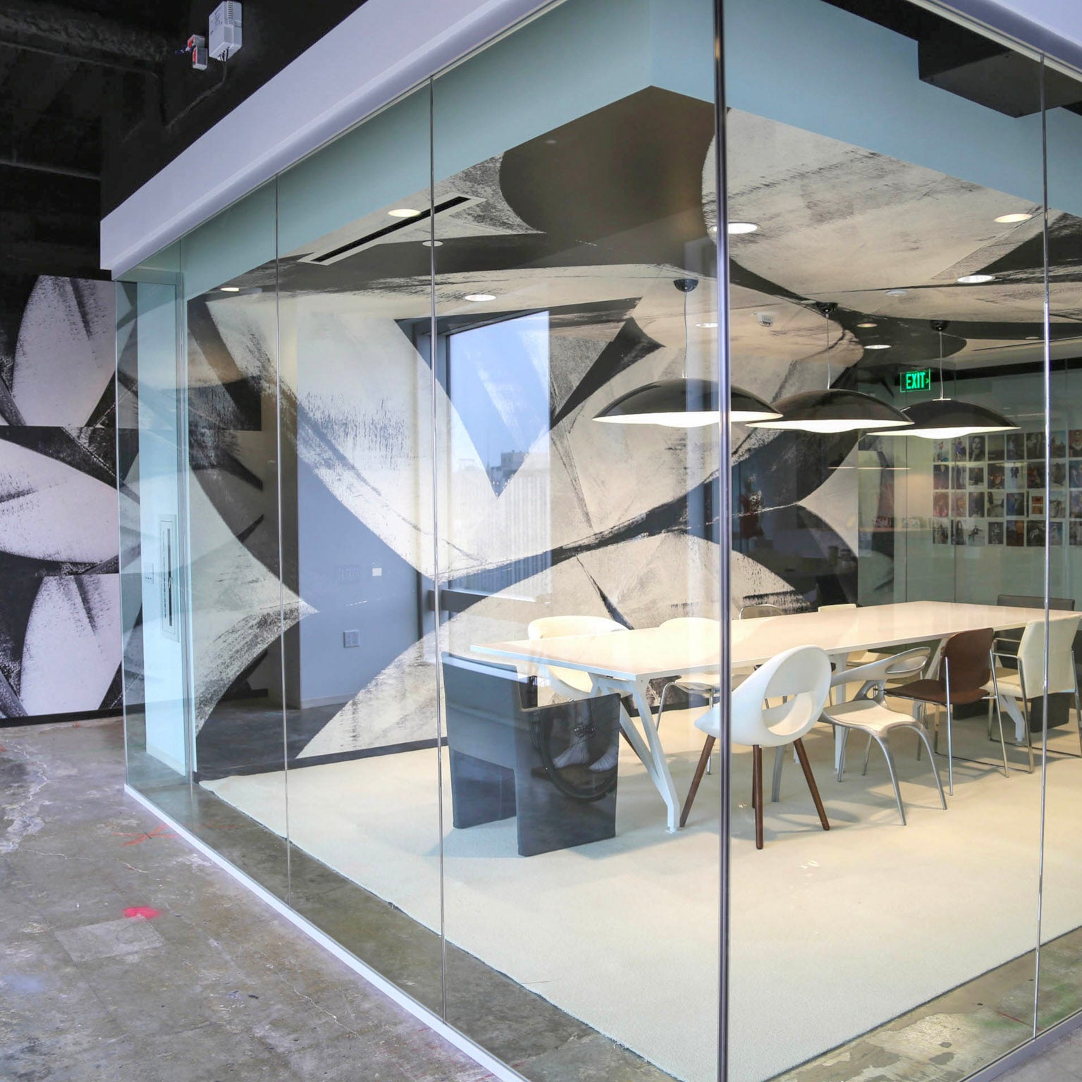 View through transparent walls of a meeting space at Brookfield Design Hive, accented by WRAPPED Studio's black-and-white mural, reflecting the innovative spirit of the Los Angeles architecture scene.