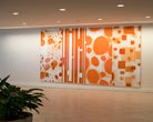 Lobby area in Centerpointe featuring a striking wall art piece with orange geometric patterns and circular motifs, enhancing the space with a modern artistic touch.