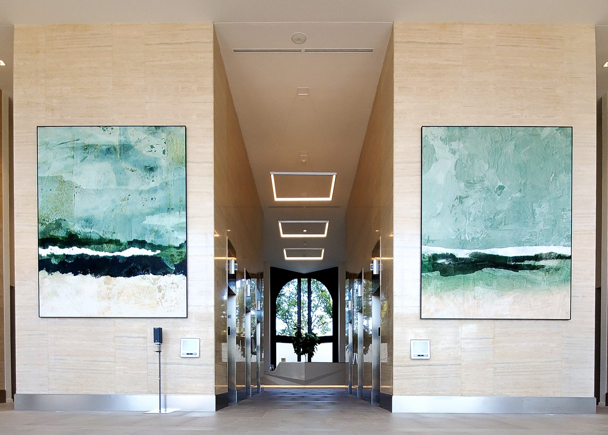 Wrapped Studio’s abstract artwork installation features two large, textured green and blue pieces, symmetrically placed in a modern lobby.