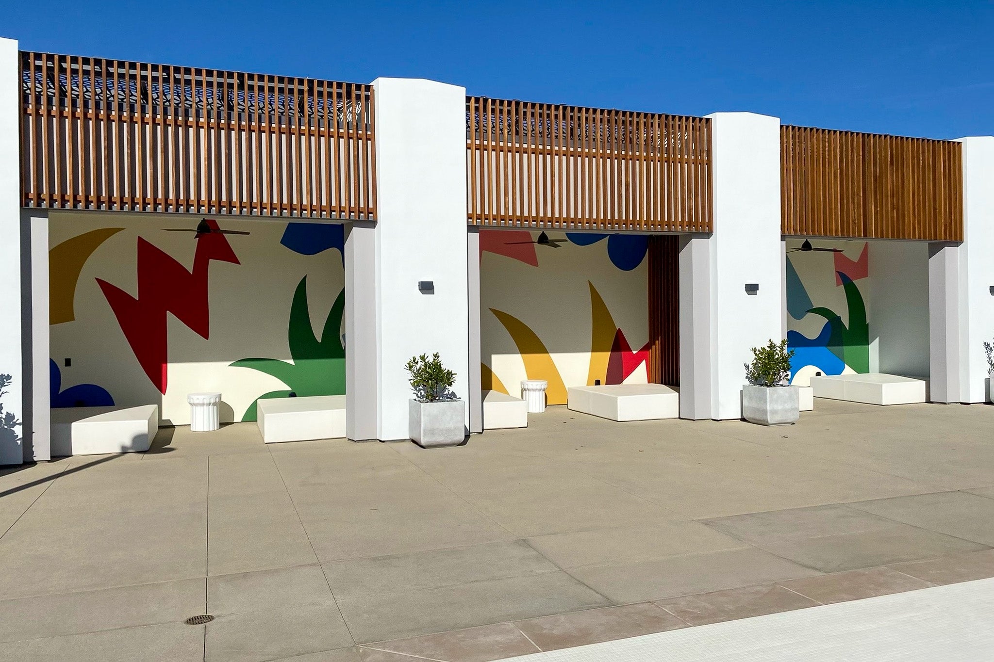 Colorful abstract murals with bold organic shapes by WRAPPED Studio, installed poolside at Confluence in Valencia to enliven the outdoor space.