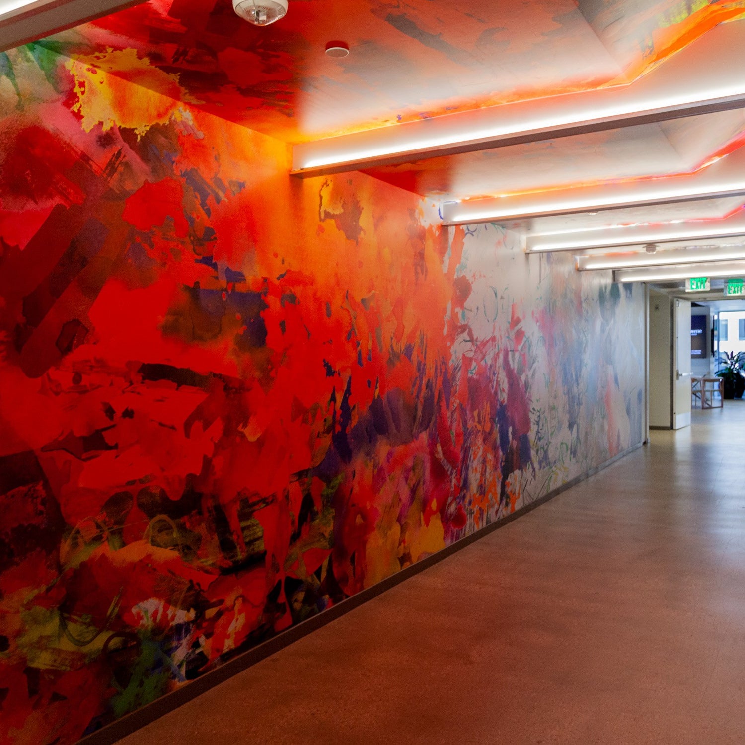 Corridor in Convene DTLA illuminated by a rich, red-toned abstract mural along the wall, enhancing the passageway with a bold artistic expression.