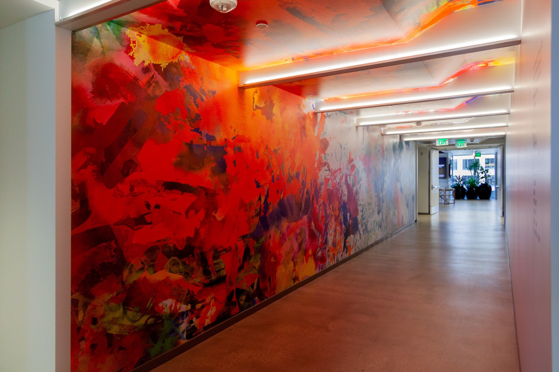Corridor in Convene DTLA illuminated by a rich, red-toned abstract mural along the wall, enhancing the passageway with a bold artistic expression.