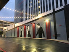 A 100-foot wide hand-painted mural by WRAPPED Studio on the exterior wall of a mid-century modern building, featuring stylized silhouettes of a man and a woman that serve as a local landmark in Long Beach.