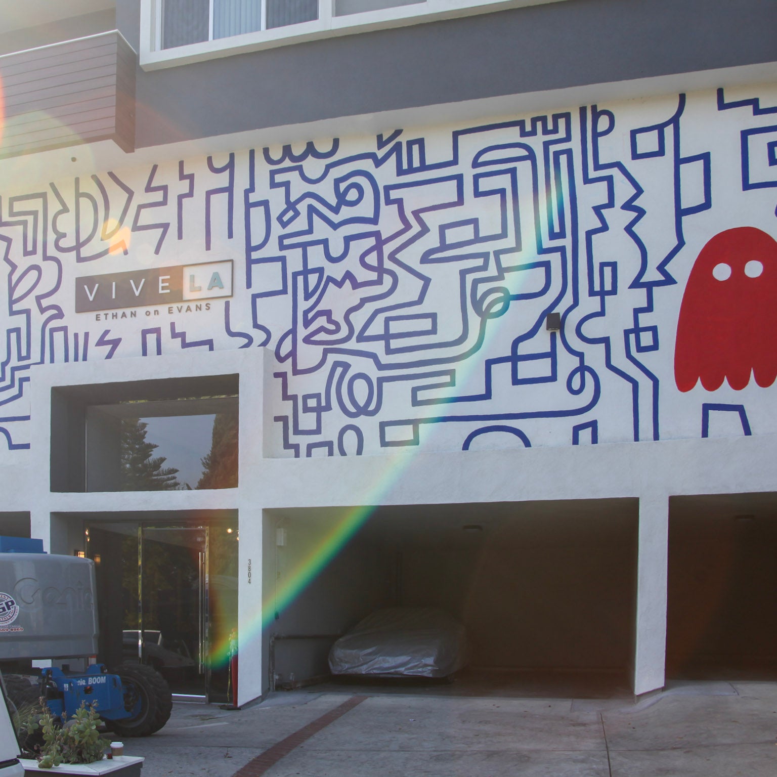 "Exterior wall of Ethan on Evans in Los Feliz with a large hand-painted mural inspired by Pac-Man, featuring a maze and iconic ghost figure, creating a playful welcome for apartment residents.