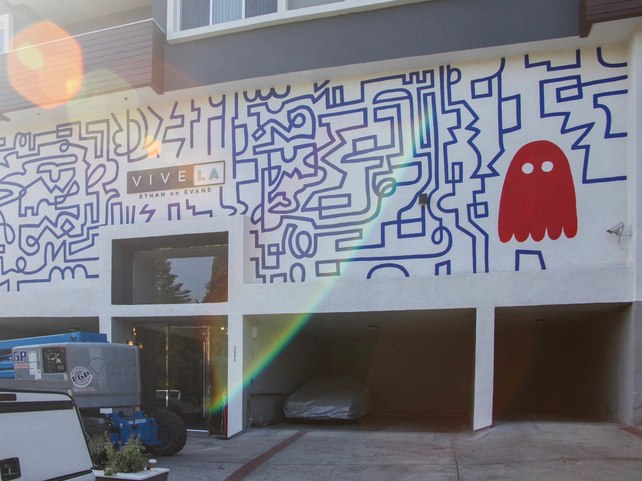"Exterior wall of Ethan on Evans in Los Feliz with a large hand-painted mural inspired by Pac-Man, featuring a maze and iconic ghost figure, creating a playful welcome for apartment residents.