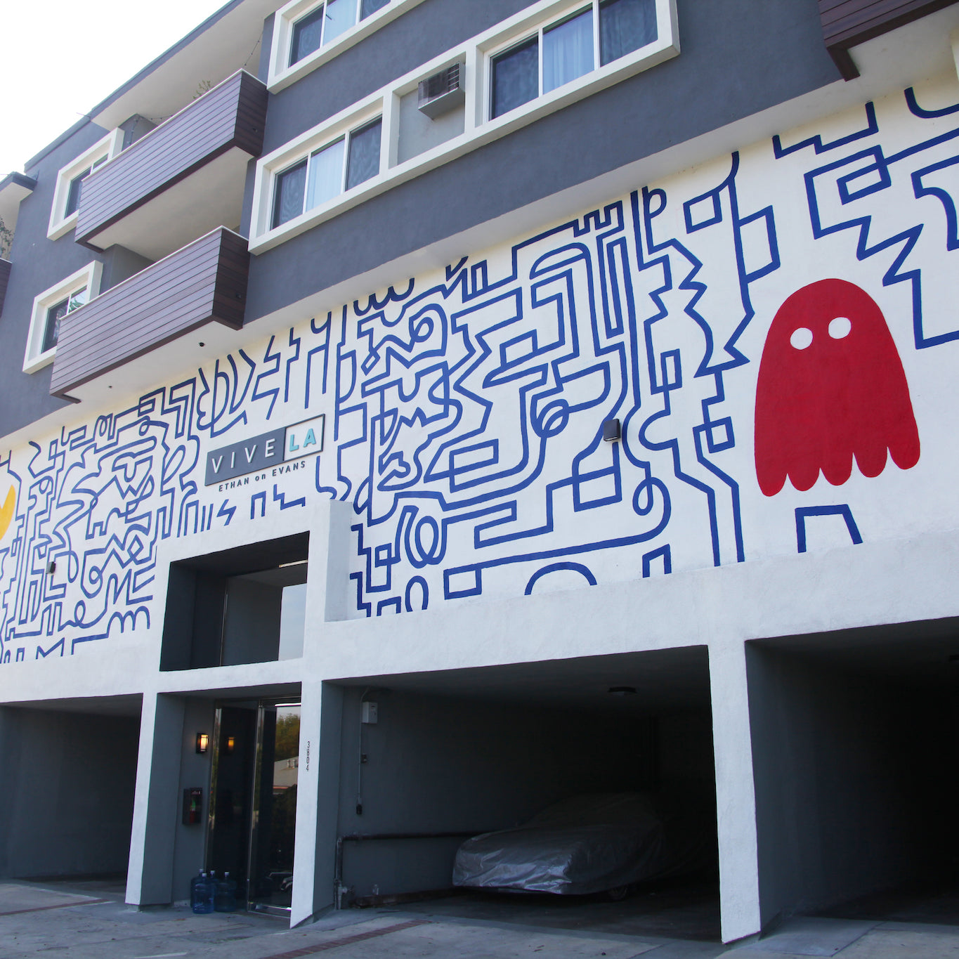Close-up view of hand-painted mural by WRAPPED Studio at Ethan on Evans, with red PacMan above the entrance, integrating classic video game nostalgia into urban living.