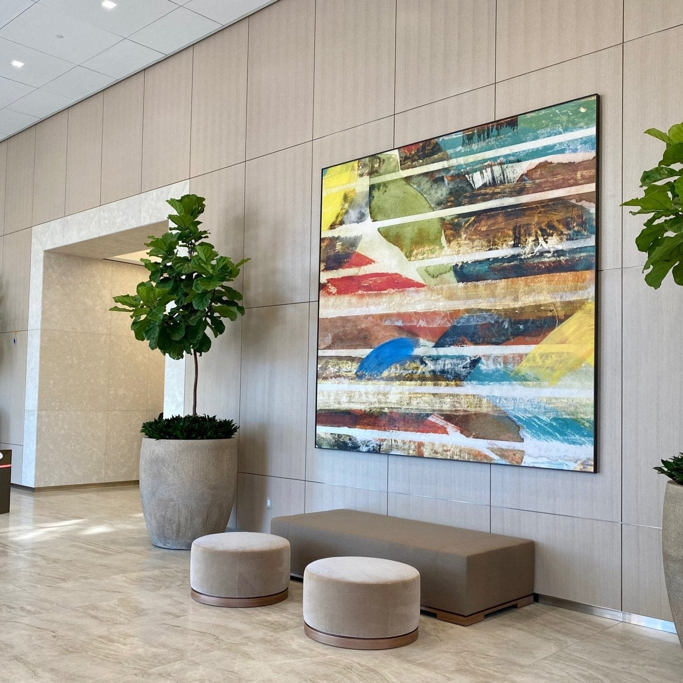 A modern lobby at Fox Plaza featuring artwork by Wrapped Studio, with a large abstract painting in vibrant stripes of red, blue, yellow, and other colors dominating the wall.