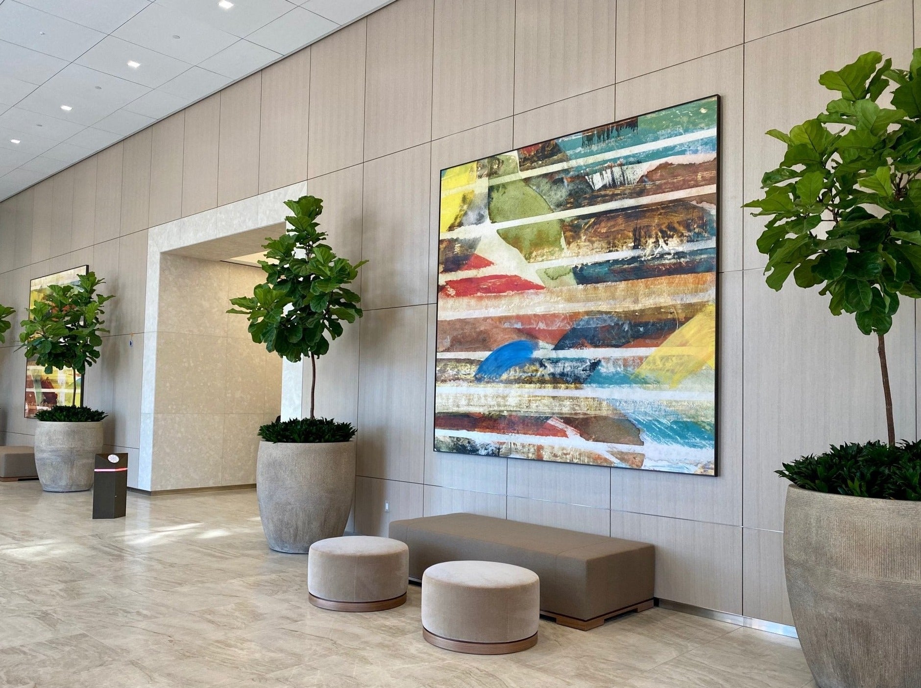 A modern lobby at Fox Plaza featuring artwork by Wrapped Studio, with a large abstract painting in vibrant stripes of red, blue, yellow, and other colors dominating the wall.