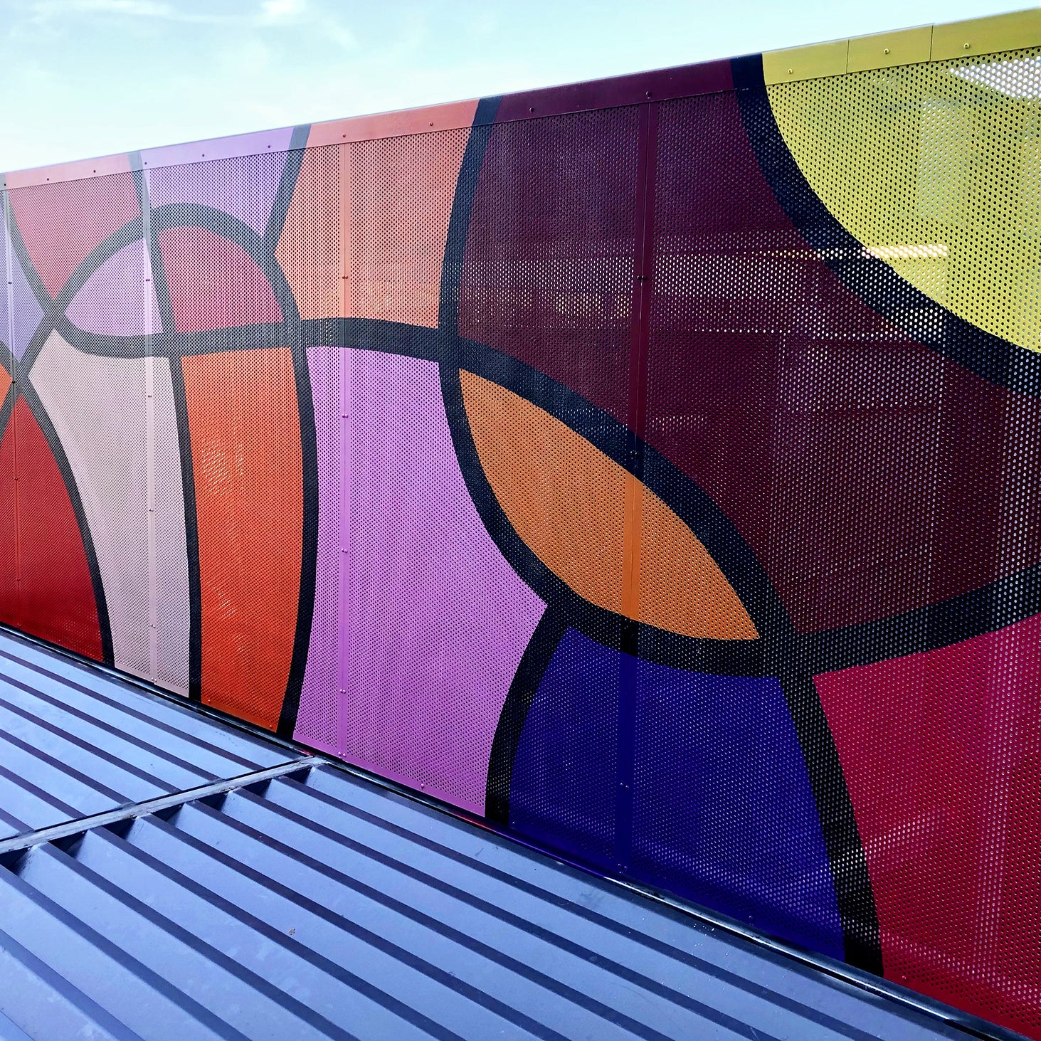 Artistic rooftop installation of an abstract mural with intertwined shapes in dynamic colors, adding a playful touch to the urban skyline.