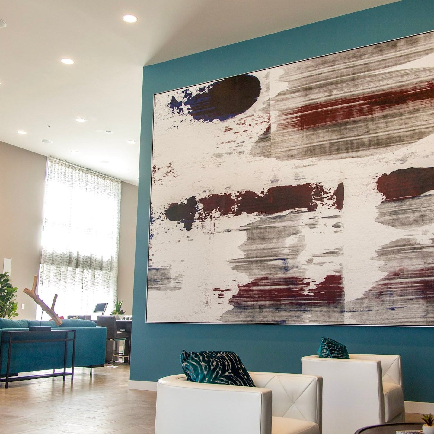 A large-format canvas painting with abstract forms in shades of brown, grey, and white hangs prominently in the reception area of Next on Sixth Apartments, mirroring the chic and modern design ethos of the space.