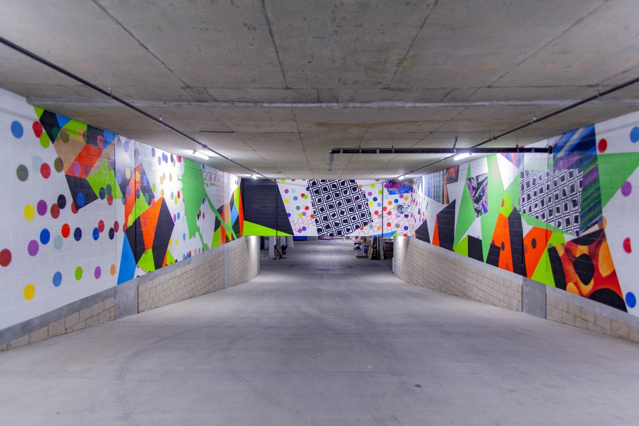 Immersive mural with bold geometric shapes, color blocks, and polka dots by WRAPPED Studio, created for the garage ramp at Next on Lex in Glendale.