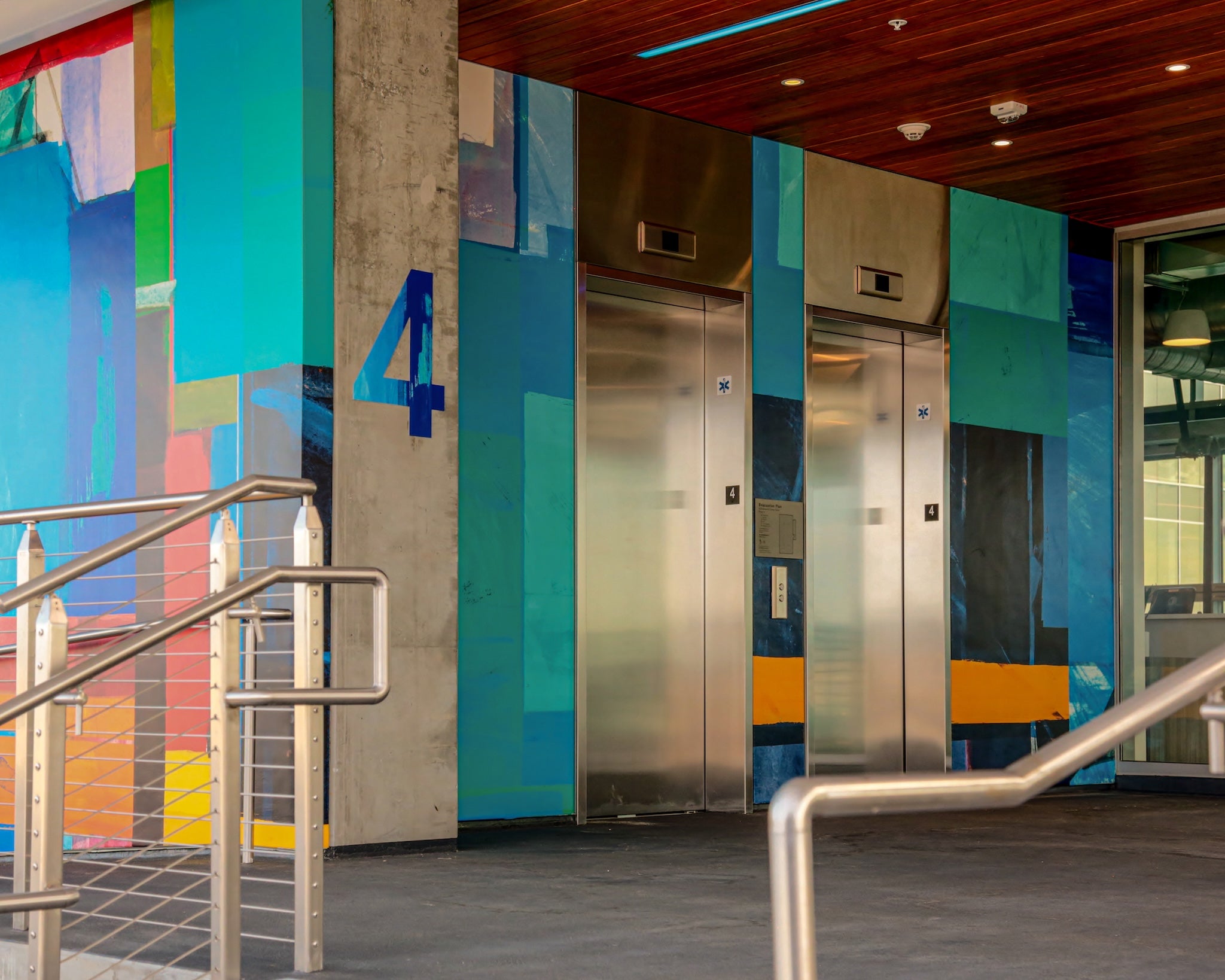 Custom hand-painted mural by WRAPPED Studio in the parking garage elevator area at America Center II, designed to support wayfinding and elevate the user experience.