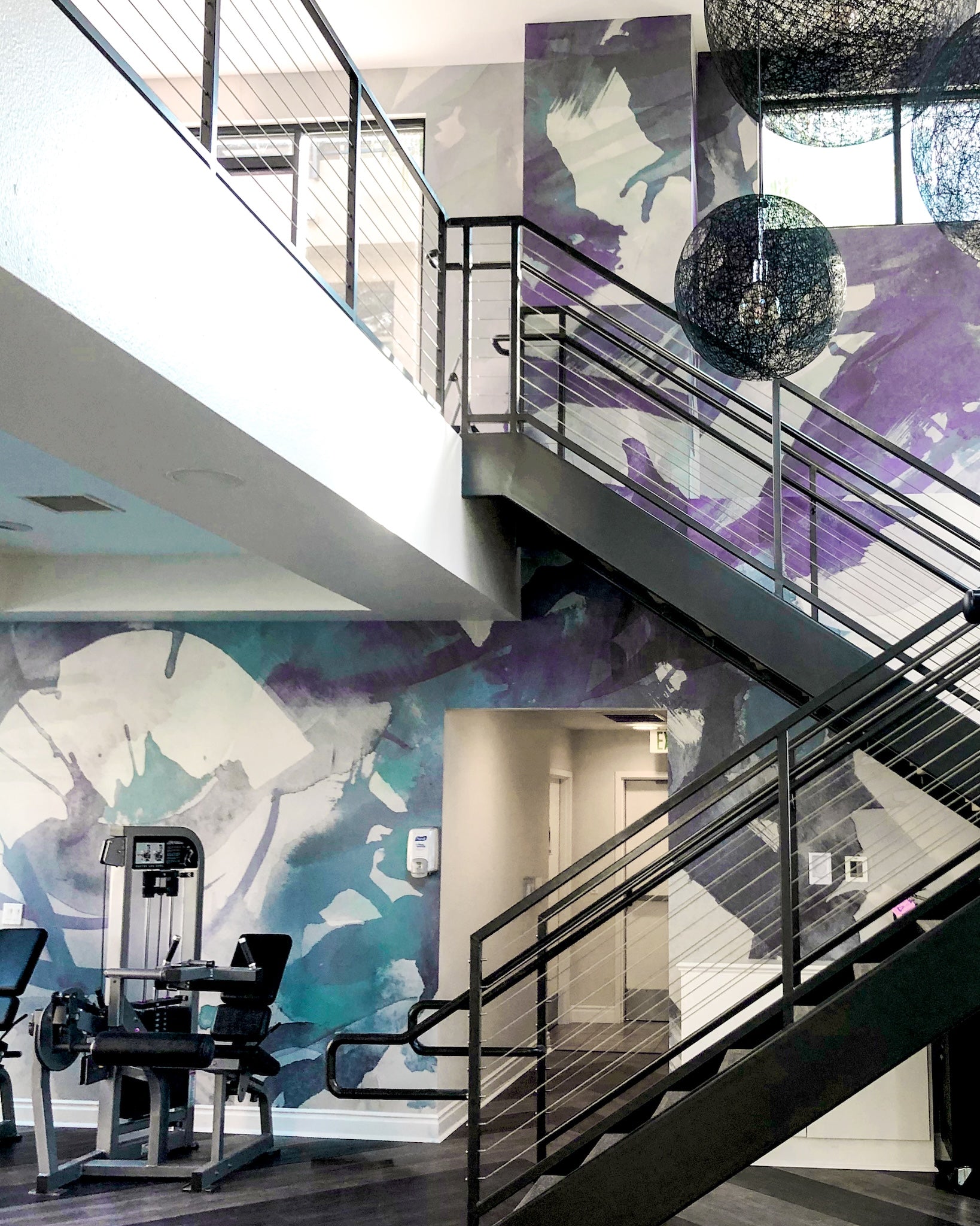 Custom abstract wallcovering by WRAPPED Studio installed in the fitness center and stairwell at Calypso multifamily community.