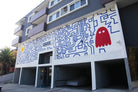 Close-up view of hand-painted mural by WRAPPED Studio at Ethan on Evans, with red PacMan above the entrance, integrating classic video game nostalgia into urban living.