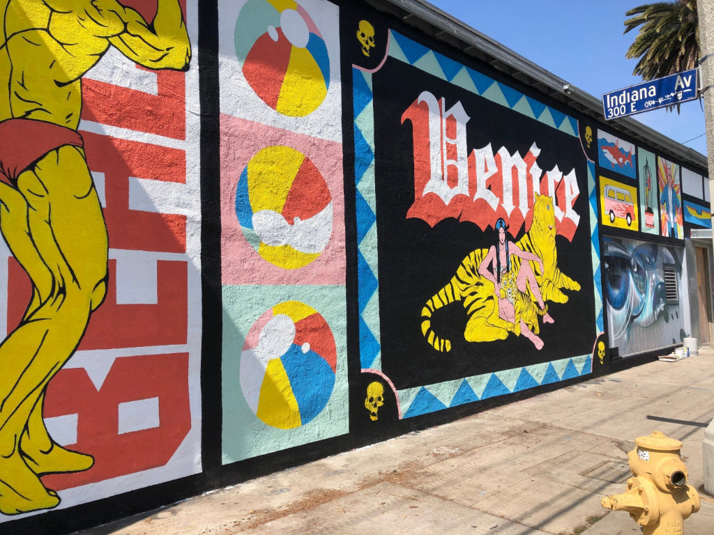 Colorful mural with various designs on a wall, featuring the word 'Venice' and a yellow figure.